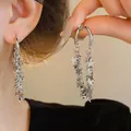 Boucles d'oreilles créoles avec pampilles étoiles argentées montrées sur main et oreille - Style Gland Étoile (38#)