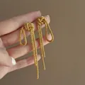 Detail shot of gold-plated metal chain knot tassel earrings showing fine texture - Small / Gold