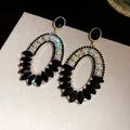 Macro view of luxurious oval drop earrings with black stones and iridescent crystals. - Oval Pendant Style / Black