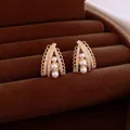 Elegant gold geometric stud earrings with pearls and crystals in a velvet jewelry tray - Gold