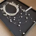 Close-up detail of a double-layer pearl beaded tassel necklace with silver chains. - White