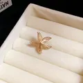 Detailed macro shot of a golden metal starfish ear clip in a beige jewelry tray - Spotted Starfish / Gold