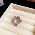 Detailed view of a silver-toned flower ear clip in a cream velvet jewelry organizer. - Flower / Silver