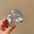 Detailed view of an irregular geometric silver-colored metal cuff bangle held in hand - Cuff Bracelet / Silver