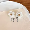 Close-up view of handmade white beaded camellia flower earrings on aesthetic paper background - Earrings / White