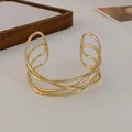 Close-up of a minimalist gold multi-layer intertwined open cuff bracelet on white background. - Style 1-Cross