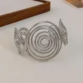 Close-up of minimalist silver-toned cuff bracelet with large spiral metal design - Style 4-Swirl