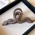 Detailed view of a matte brown wavy acrylic hair claw clip on a jewelry display board - Wave Twisted Style / Brown