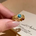 Detailed view of vintage gold-plated open ring featuring a round turquoise stone - Retro Artificial Turquoise Style
