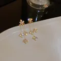 Primo piano di eleganti orecchini a nappa con cristalli floreali e foglie - Ago In Acciaio N. 15 - Ecologico - Zircone - Dorato