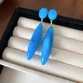 Primer plano de pendientes de gota de acrílico azul jaspeado en joyero elegante - Azul