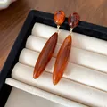 Primer plano de pendientes de gota de acrílico ámbar en bandeja de joyas beige. - Café Oscuro