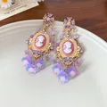 Close-up detail of vintage style cameo earrings with purple floral tassels and gold finish - Stud Earrings (WE4001) / Pink And Purple (WE4001)