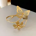 Close-up of gold-plated butterfly and flower open bangle with a central rhinestone detail - Flower And Butterfly Combo (HB2500)