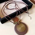 Detaillierte Nahaufnahme der ethnischen Vintage-Kette mit Spiral-Metallanhänger - Halskette-Gold-Braun