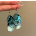 Gros plan détaillé de boucles d'oreilles à pompons en nacre bleue tenues à la main - Style de Gland en Tranche de Coquille (3#)
