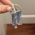 Elegant silver needle earrings with colorful zirconia and pearl tassels shown in hand - Blue Gold Tassel (62#)