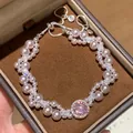 Primo piano di elegante bracciale a doppio strato con perle, zirconi e gemma rosa - Rosa