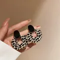 Close-up of stylish acrylic geometric earrings with black and white grid pattern - Black With White Stone