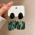 Close-up of green marble acrylic square earrings with black oval stud detail - Dark Green Marble