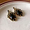 Nahaufnahme von goldenen Vintage-Ohrringen mit eleganten schwarzen Kristallfassungen. - Silber-Ohrstecker-Stil / Ohrringe-Gold-Schwarz