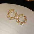 Gros plan de boucles d'oreilles clips en forme de C torsadé avec perles et zircons - Boucles d'oreilles à clip / Or