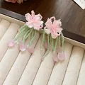 Close-up detail of forest style flower earrings with green seed bead tassels and charms - Style 28 / Pink/Green