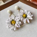 Detailed macro view of elegant white fabric flower earrings with woven raffia beads - White