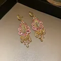 Macro detail of vintage ethnic dangle earrings with pink crystals and teardrop tassels - Gold-Pink Hook Style