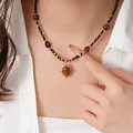Collana vintage bohémien con perline occhio di tigre e ciondolo a sole etnico su un modello - Collana No. 25 (Acciaio al Titanio Nero-Marrone)