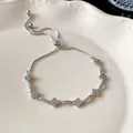 Close-up of elegant silver adjustable bracelet with zircon flower charms on ceramic tray. - Rhombus Flower Bracelet / Silver