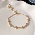 Detailed view of the sparkling zircon flower charms on the adjustable gold-tone bracelet - Rhombus Flower Bracelet / Gold