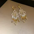 Detailed view of vintage ethnic earrings with clear rhinestones and golden tassels - Ear Hooks - Gold - White