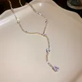 Close-up of elegant Y-shaped gold necklace with sparkling teardrop zircon crystals. - Gold