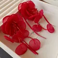 Primo piano di orecchini a fiore in rete rossa con delicati pendenti in perline di vetro - Rosso