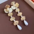 Detailed macro shot of 18K gold-plated floral earrings with zircons and pearl drops. - Flower Pearl Style / Gold