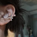 Close-up of zircon-studded ear cuff with a dangling cross pendant on model's ear. - Single Left Ear / Silver