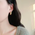 Minimalist gold metal hoop earrings with a twisted design shown on a female model - Style 3 / Gold