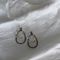 Close-up of minimalist irregular interlocking metal hoop earrings on white lace fabric - Style 2 / Gold