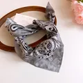 Close-up of a gray paisley print bandana scarf on a decorative wooden tray. - Gray