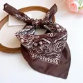 Close-up detail of a brown sunflower print silk scarf arranged on a wooden display tray. - Brown