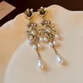 Detailed close-up view of vintage court style gold flower earrings with white pearl drops - Gold