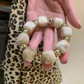 Close-up of acrylic marbled cube beads and gold-toned accents on a chunky bracelet. - Bracelet / White-Gold
