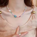 Nahaufnahme einer farbenfrohen Perlenkette mit Seestern-Anhänger am Hals eines Models. - Stil 17 Blauer Seestern Gänseblümchen Bunte Perle