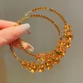 Close-up of oversized gold-tone hoop earrings with sparkling amber water-drop crystals. - Champagne