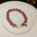 Close-up of pink crystal bead bracelet with shell gourd charm and golden Fu tag - Gourd Fu Pendant Style / Red/Pink