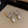 Detailansicht eleganter blumenförmiger Kristallohrringe mit weißen birnenförmigen Perlen - Ohrringe