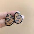 Primer plano detallado de pendientes de botón vintage con estampado de leopardo. - Café Negro