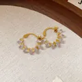 Dettaglio ravvicinato di orecchini a cerchio placcati oro 18k con cristalli trasparenti - Oro