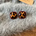 Elegantes pendientes de leopardo vintage con borde rojo sobre fondo de piel gris - Redondo Rojo